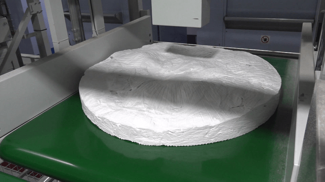 Large bundle of white fabric on green conveyor belt