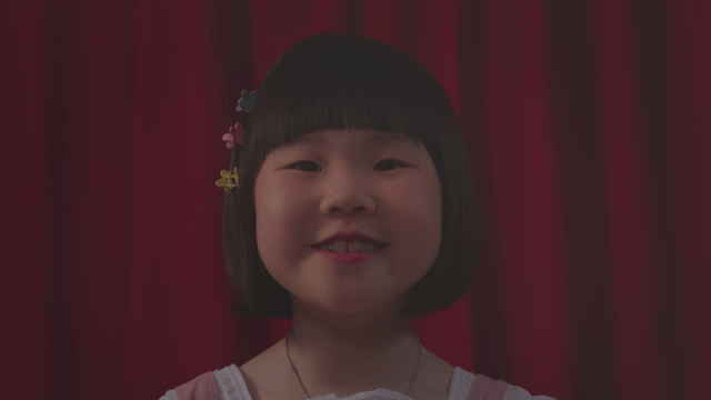 Girl smiling and talking in front of a red curtain