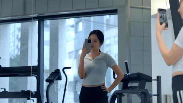 Young woman taking a selfie in gym mirror