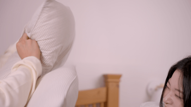 Young woman laughing during playful pillow fight