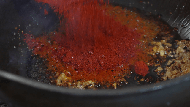 Chili powder poured into sizzling pan