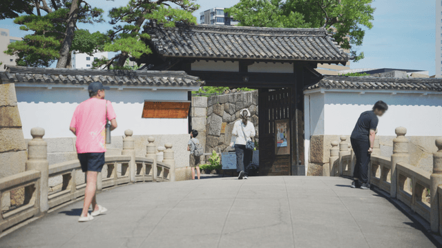 People walking on a bridge towards a traditional gate