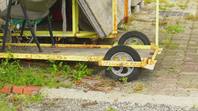 Rusty cart wheel with overgrown weeds
