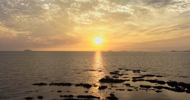 Sunset over a calm ocean with distant islands