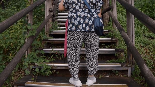 An elderly woman climbing outdoor stairs