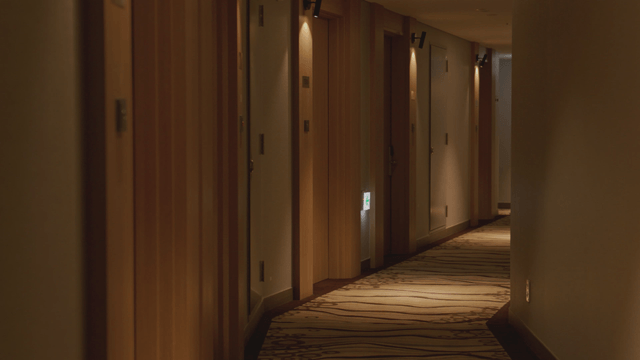 Woman peeking out from a quiet hotel corridor
