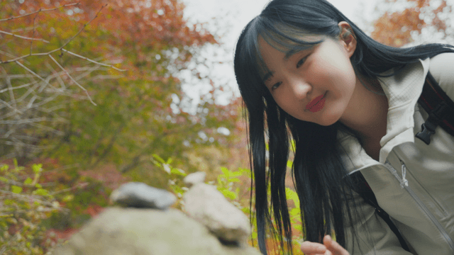 Young woman stacking stones in forest