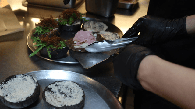 Chef preparing premium black burger in kitchen