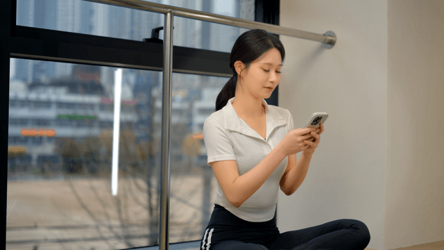 Young woman using smartphone while sitting by window
