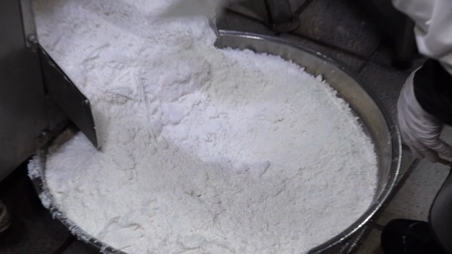 A worker organizing glutinous rice flour coming out of a machine