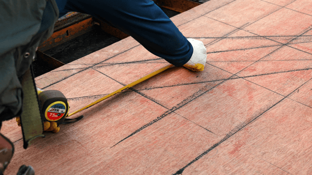 Worker measuring plywood with a tape measure