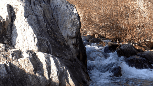 Fast-flowing winter stream beside a giant rock