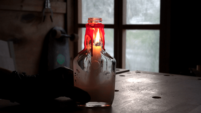 Candle burning in a glass bottle indoors