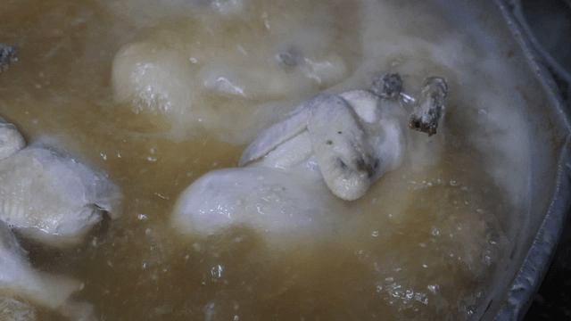 Chicken boiling in a pot of broth