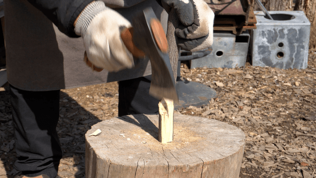 Woodcraft artisan shaping wood with an axe outdoors