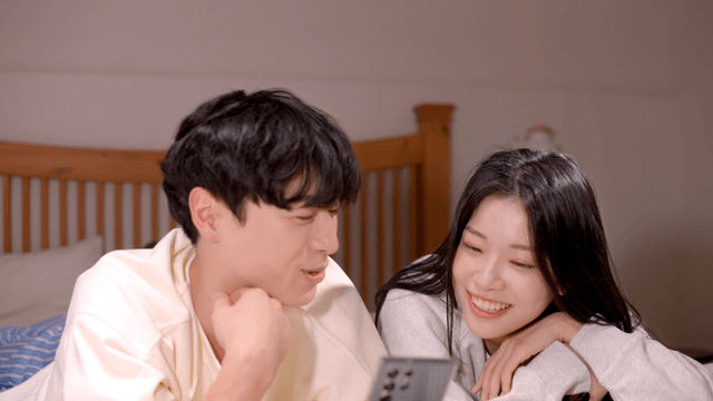 Couple chatting on bed while looking at phone