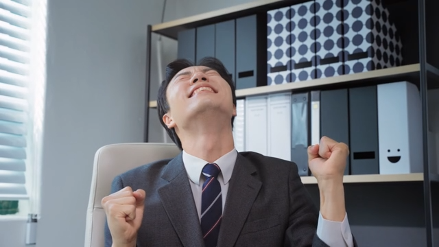 책상에 앉아 환호하는 사업가