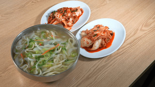 Hand-cut noodle soup and kimchi on table