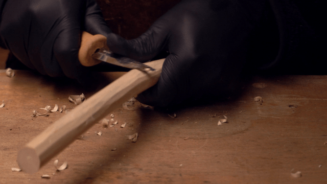 Hands carving wood with precision