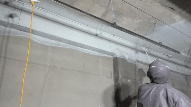 Worker spraying paint on bare concrete