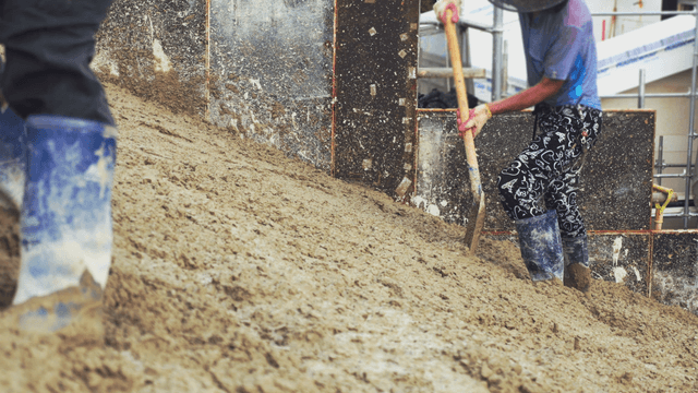Worker shoveling concrete at a construction site