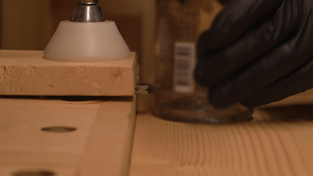 Gloved hands handling glass bottle