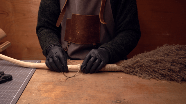 Craftsman wrapping a broom handle