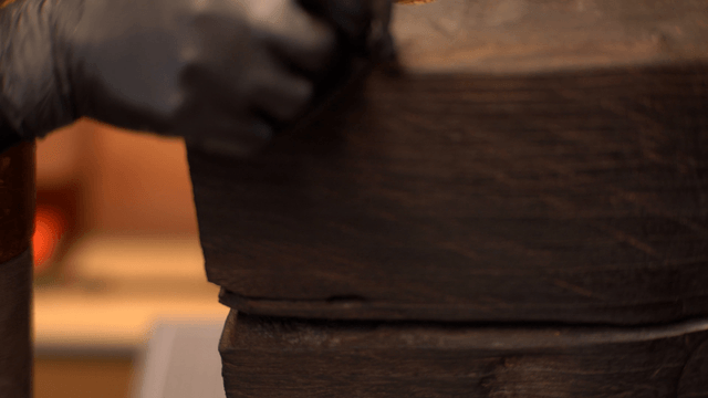 Artisan polishing a wooden sculpture with black gloves