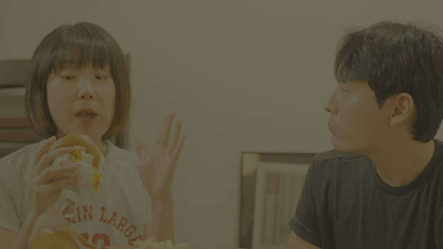 Man and a woman enjoying hamburgers at home