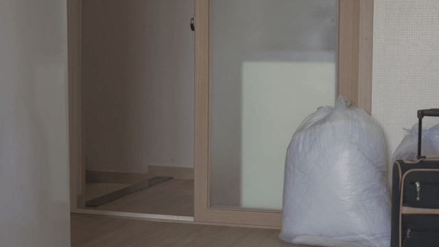 Woman leaving an empty house carrying a box