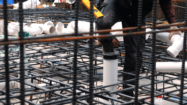 Worker installing pipes on a construction site