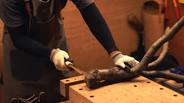 Person cutting a branch on a workbench