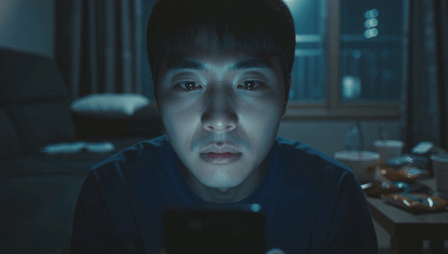 Man focused on his phone in a dim room