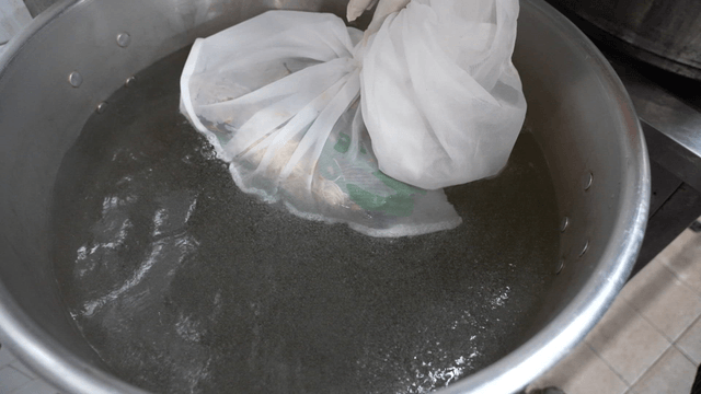 Cloth stock bag lowered into large pot of hot water
