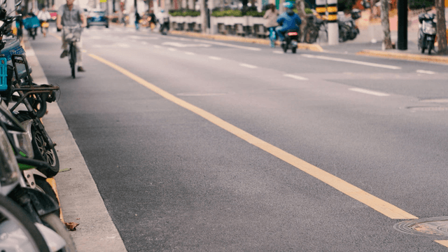 Busy road with passing bicycles and cars