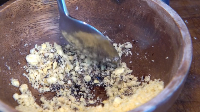 Crushed snacks mixed with sauce in a wooden bowl