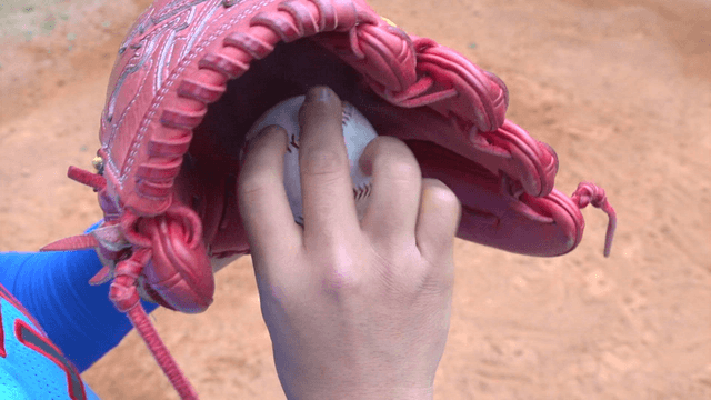 Hand holding baseball inside glove