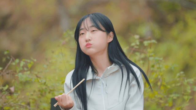 Young woman eating gimbap on autumn mountain trail