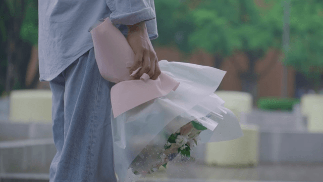 Man holding a bouquet in rainy park