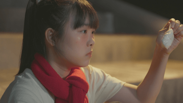 Girl sitting on the steps wearing a red scarf and looking at ice cream
