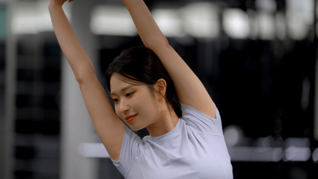 Stretching arm extended by young woman in gym
