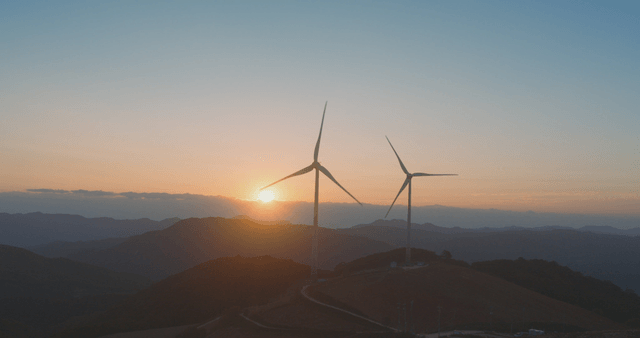 산 위로 해가 뜨는 풍력 터빈
