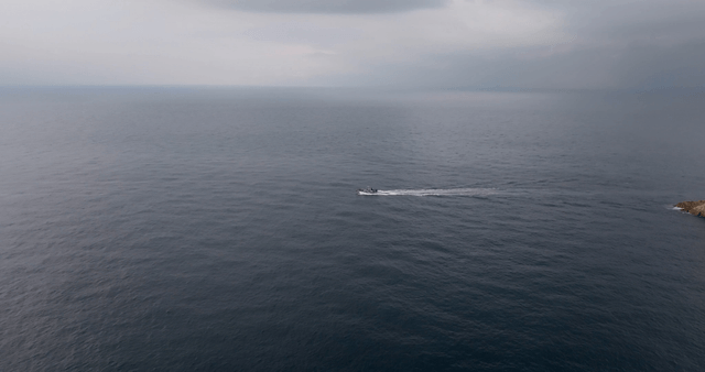 A boat sailing near a rocky coastline