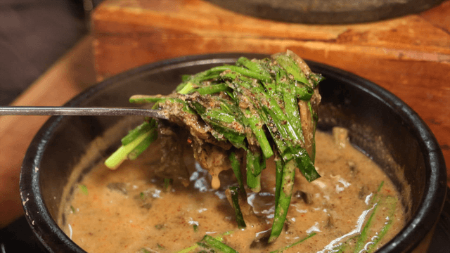 Spoon serving loach soup from earthen pot