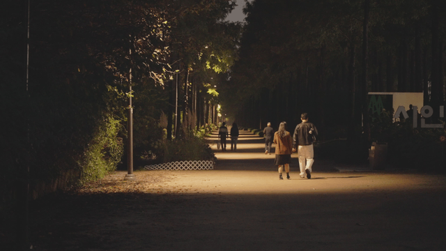 People walking along a dimly lit park path at night