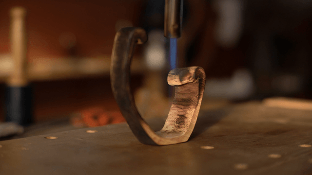 Artisan burning patterns on wood piece with torch