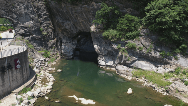Tunnel and clear valley stream between rocky cliffs