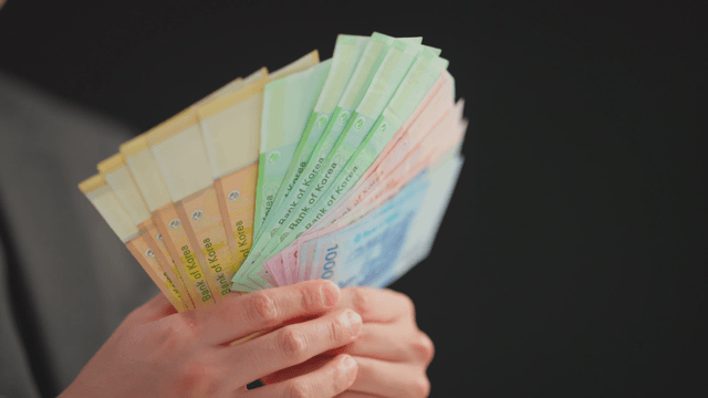 Hands holding Korean banknotes