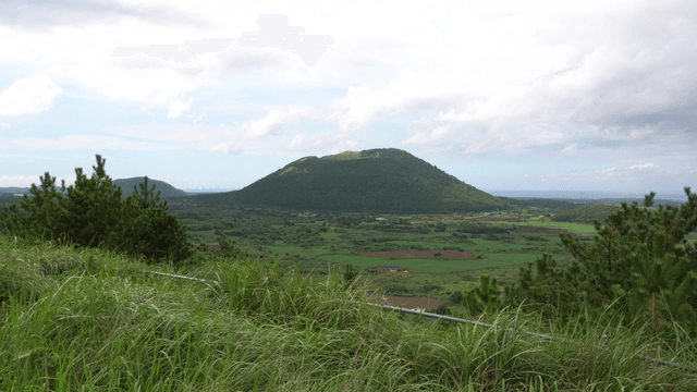Green hill under cloudy sky