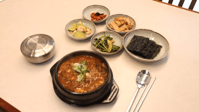 Korean side dishes and hot gatgimchi stew on restaurant table